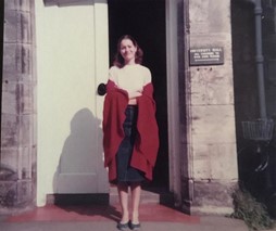 Female student in St Andrews red gown, outside a doorway