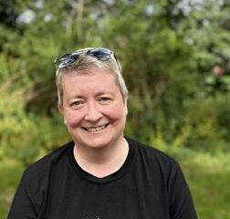 Colour photo of a woman with short blonde hair in a black t-shirt