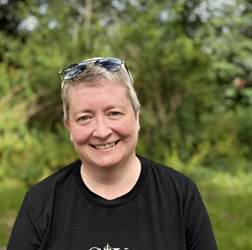 Colour photo of a woman with short blonde hair in a black t-shirt